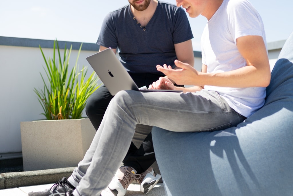 Two young men working together on their laptop